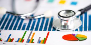 Stethoscope And Us Dollar Banknotes On Chart Or Graph Paper, Fin